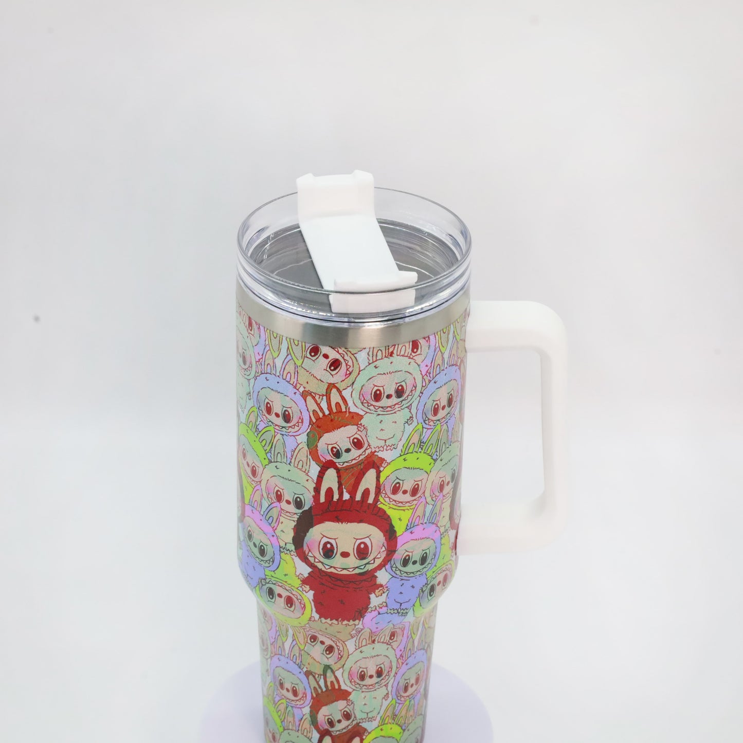 A stainless steel tumbler with a white handle, covered in a dense pattern of colorful Labubu characters dressed in bunny suits, with a central red bunny standing out.