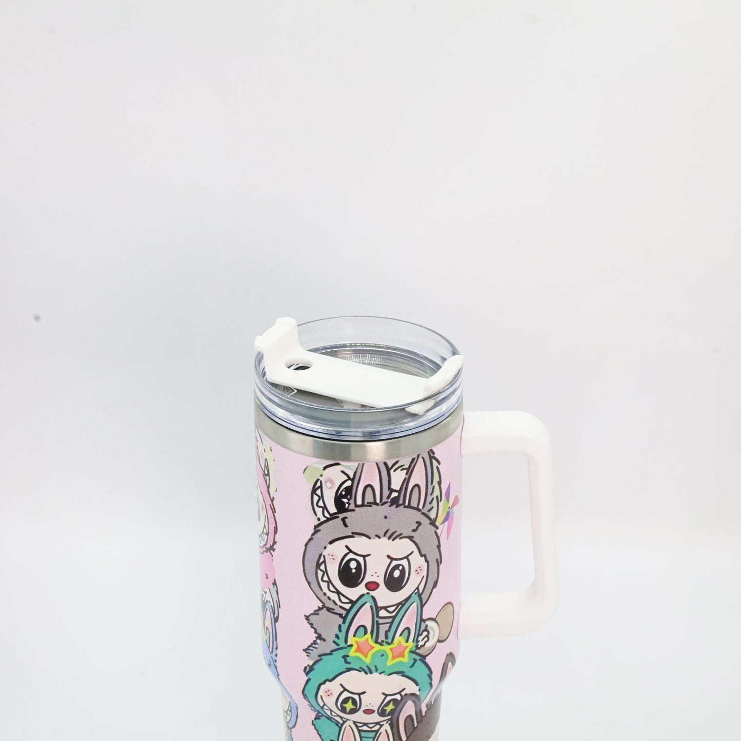 A pastel pink tumbler with a white handle and lid, featuring Labubu characters in antler and bunny costumes, with a clear straw lid and stainless steel rim.