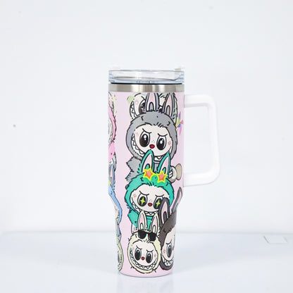 A pastel pink tumbler with a white handle and lid, featuring Labubu characters in antler and bunny costumes, with a clear straw lid and stainless steel rim.