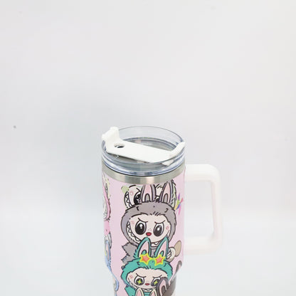 A pastel pink tumbler with a white handle and lid, featuring Labubu characters in antler and bunny costumes, with a clear straw lid and stainless steel rim.